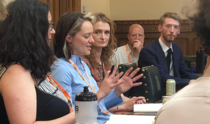 A woman gestures with her hands to explain labour exploitation to a panel of people